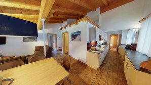 Amplia sala de estar con techo de madera, una mesa de comedor y una cocina con lavaplatos y armarios.