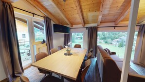 Un comedor con una mesa de madera, sillas, un banco y un televisor.