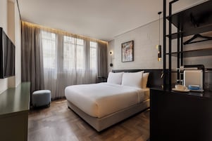 Habitación de hotel con una cama grande, un escritorio, una silla, un armario y un radiador.