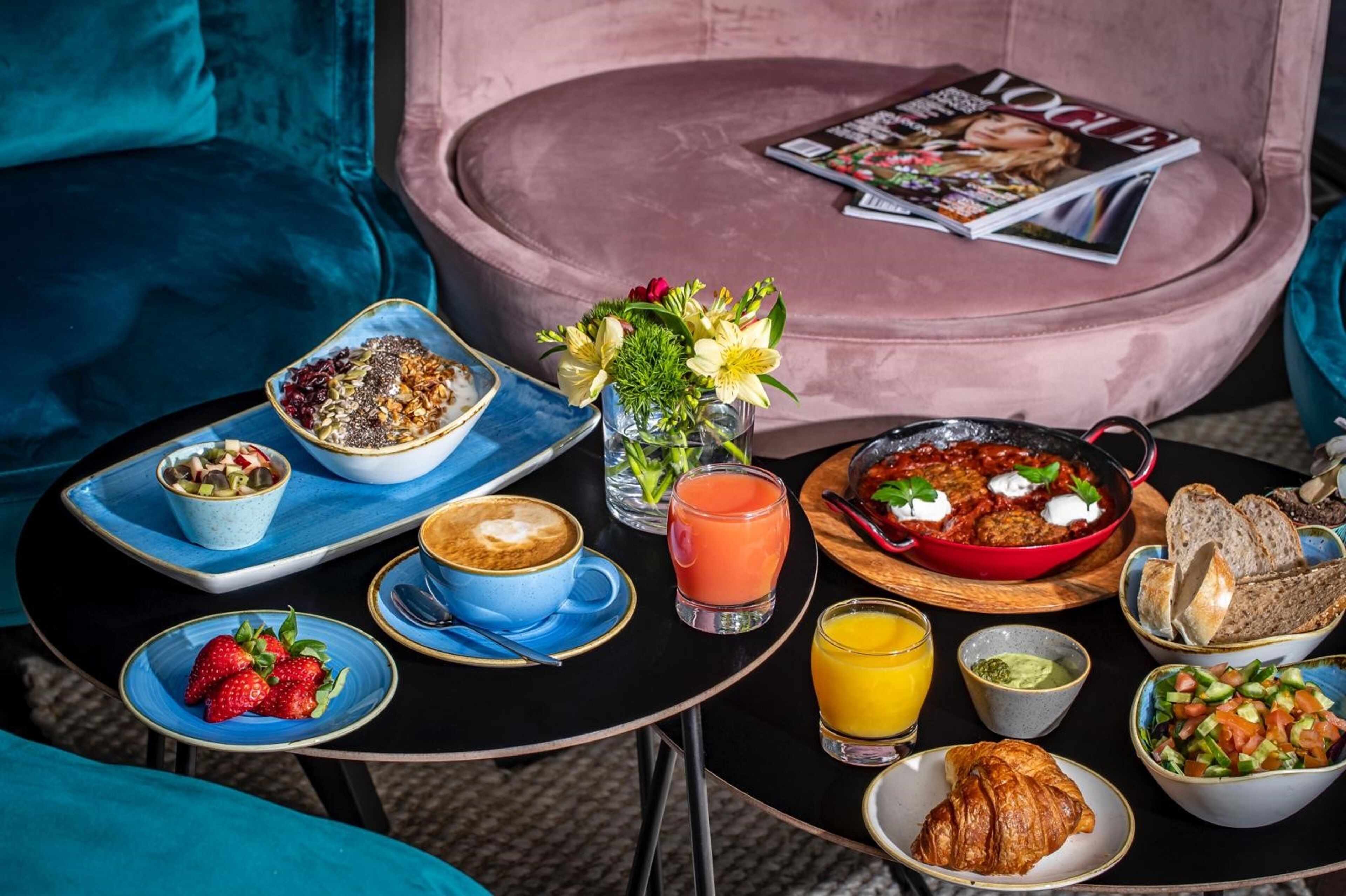 Desayuno con una variedad de platillos, incluyendo un croissant, fruta y una sartén roja con huevos.