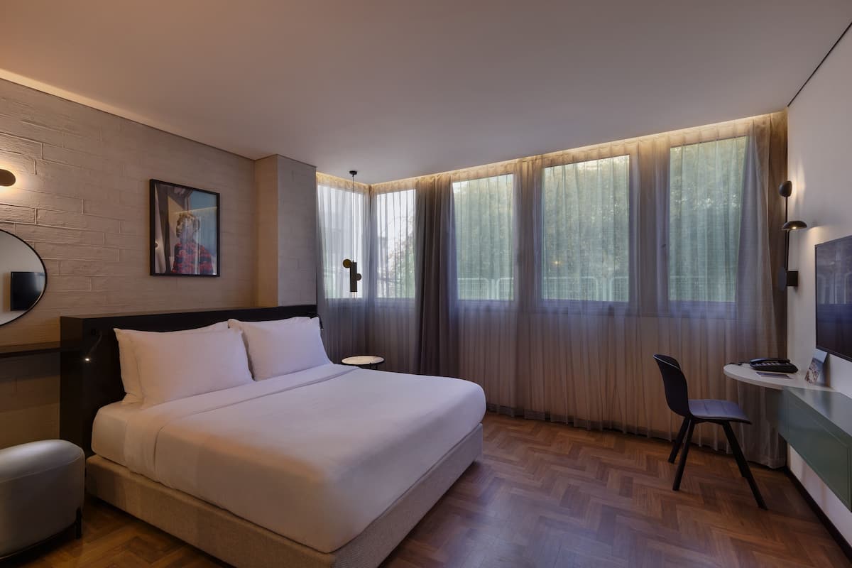 A modern hotel room with a large bed, a desk, and a chair.