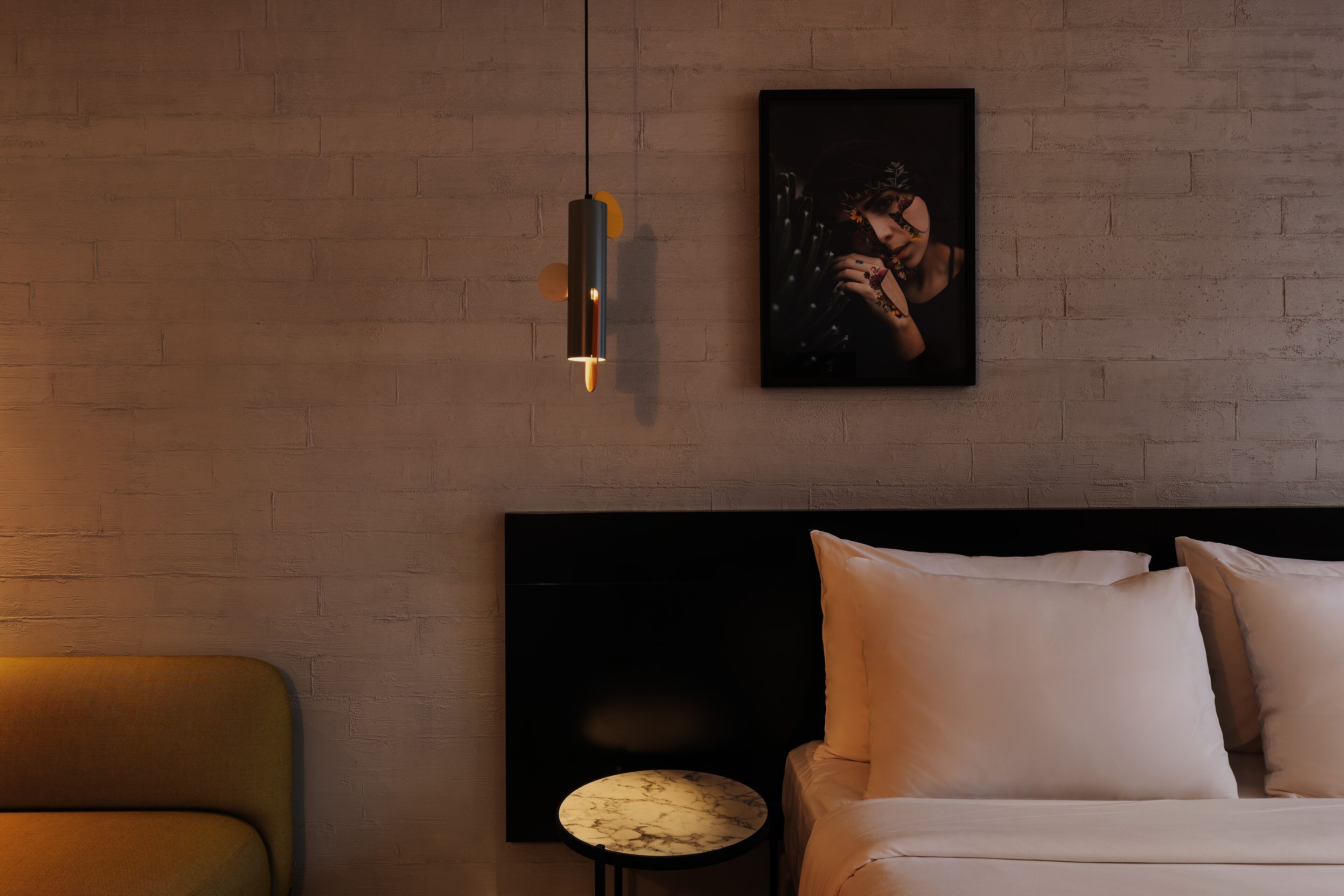Ein modernes Schlafzimmer mit Backsteinwand, einem Bett mit weißer Bettwäsche, einem runden Beistelltisch und einer Pendelleuchte.