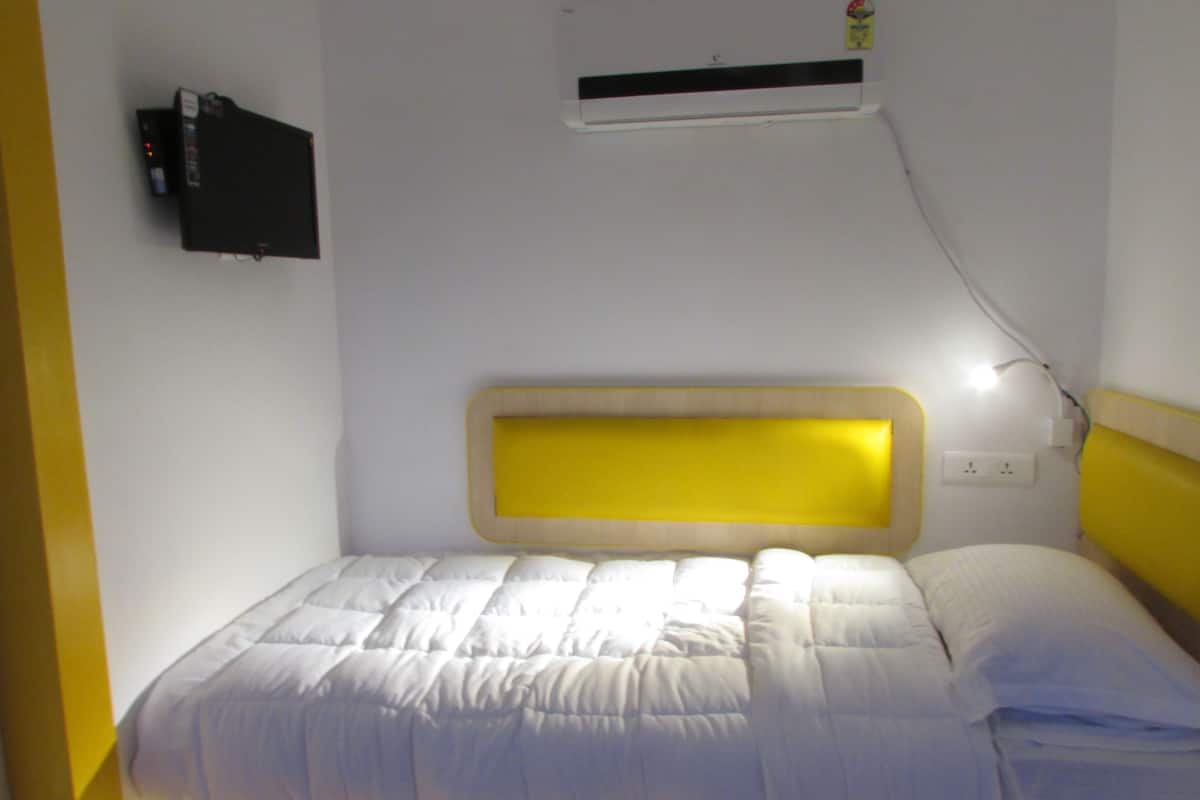 Un letto singolo con testiera, un condizionatore d'aria a parete e una presa di corrente.