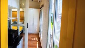 A narrow hallway with a kitchen area on the left, a white door in the center, and a large window on the right. - Stay Inn (Bhopal)