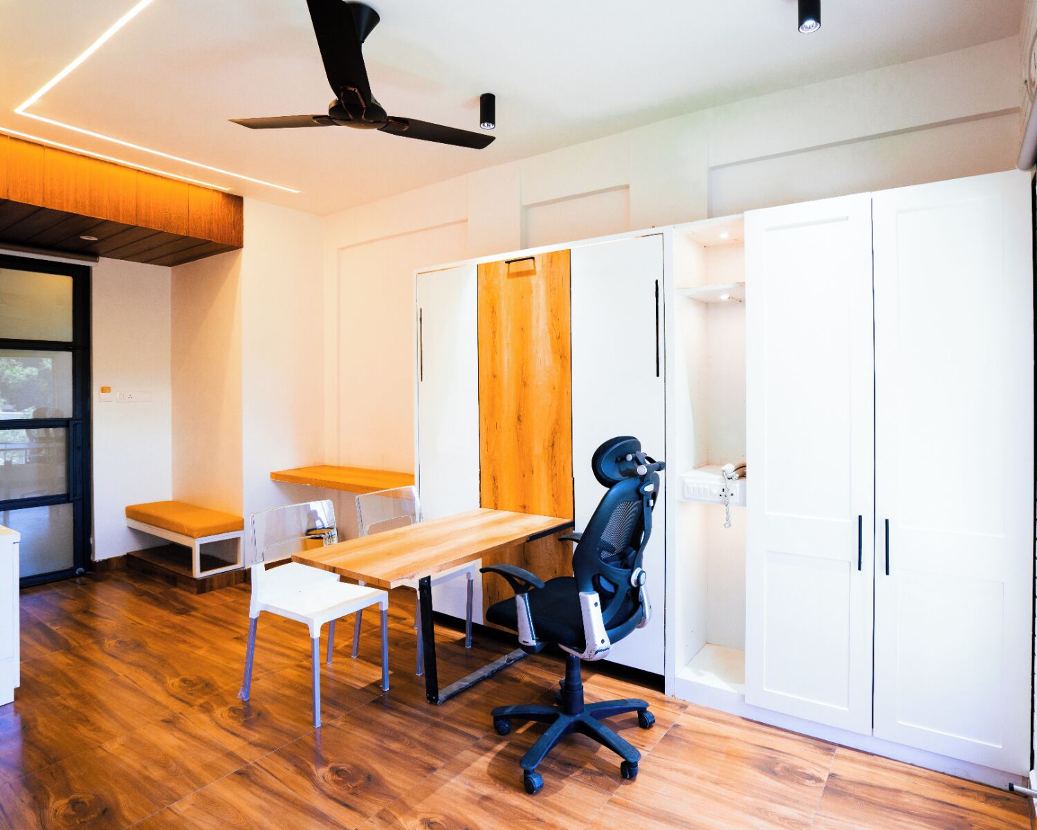 A modern office space with a wooden desk, office chair, and white cabinets.