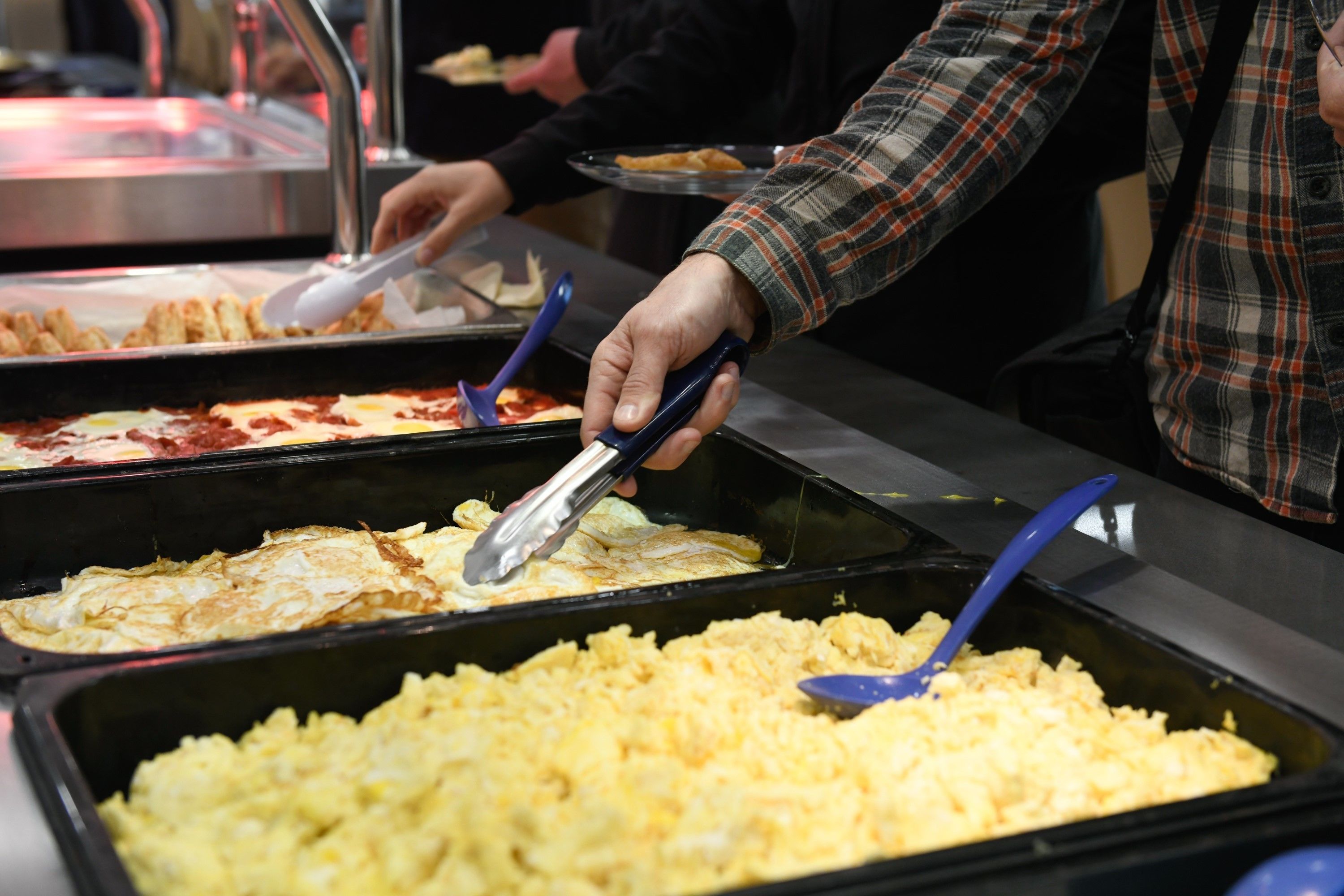 A buffet with various food options, including omelets and scrambled eggs.