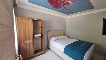 Un dormitorio con una cama, un armario y un mural floral rosa en el techo.