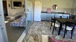 A modern kitchen with a dining area, a sofa, and a TV. - Cosy Park Apartment (Yomra)