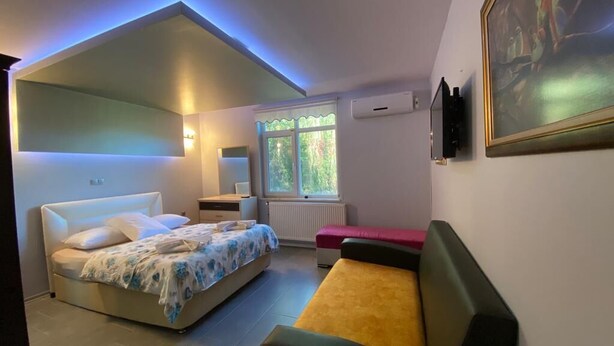 A bedroom with a bed, a bench, a desk, and a window. - Cosy Park Apartment (Yomra)