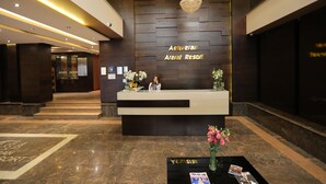Un mostrador de recepción en Ashveran Ararat Resort con un diseño moderno, un candelabro y un área de recepción con mostrador y flores.