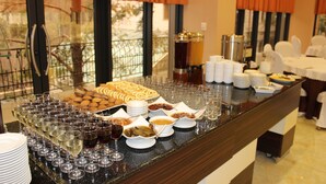 Una mesa de buffet con diferentes alimentos y bebidas, incluyendo copas de vino y platos.