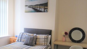 Una camera da letto con un letto, una scrivania, una sedia, un quadro e una finestra.