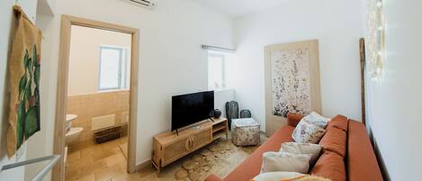 A living room with a sofa, television, and a small table.