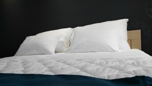 Ein Bett mit weißer Bettwäsche und einer dunkelblauen Decke.