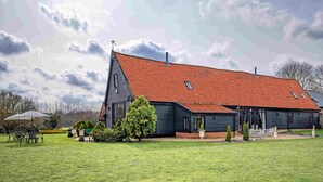 A large house with a red-tiled roof, a dark exterior, and a well-maintained lawn. - Doves Barn (Ipswich)