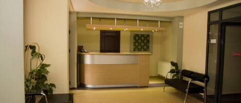 A reception area with a reception desk, a bench, and a chandelier.
