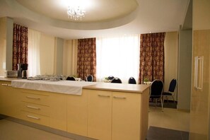 A modern kitchen with a central island, two pendant lights, and a dining area with chairs and a table.
