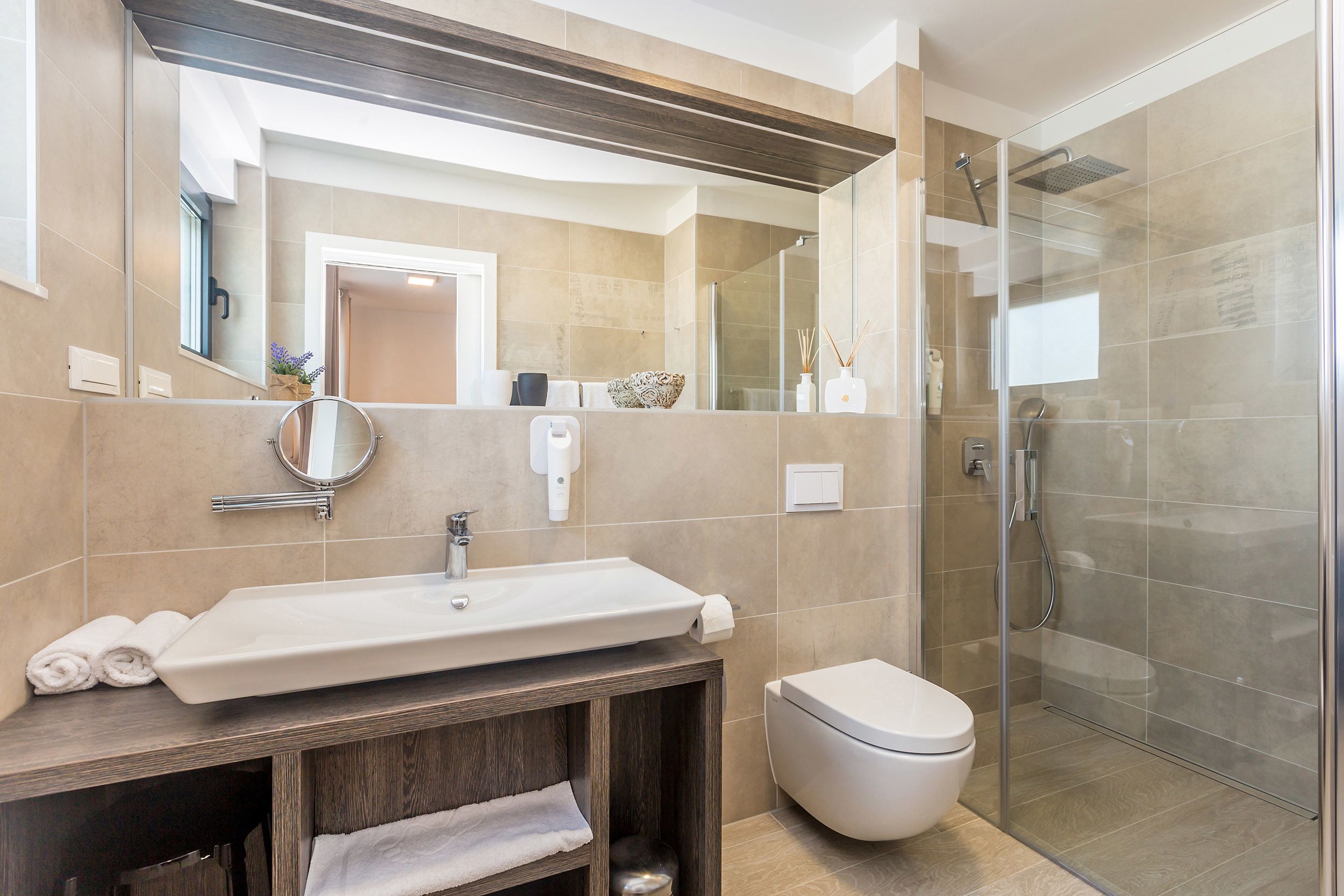 Une salle de bain moderne avec un grand lavabo, un miroir et une douche à parois de verre.