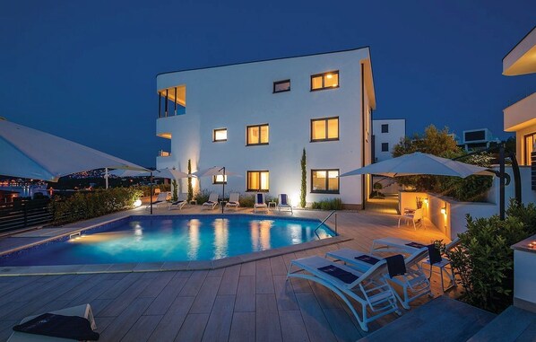 Ein modernes Gebäude mit Schwimmbad, Sitzgelegenheiten im Freien und einer gut beleuchteten Terrassenfläche.