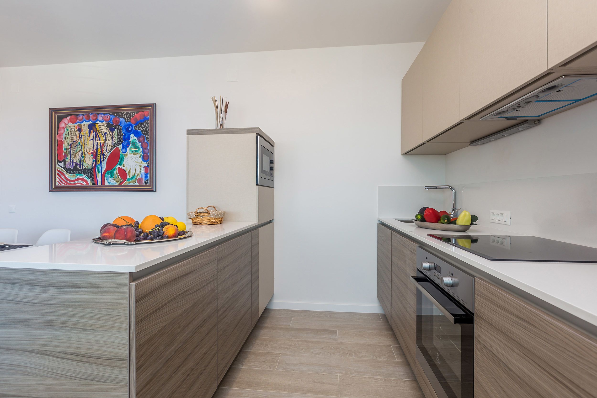 A modern kitchen with a wooden countertop, a built-in oven, and a wall-mounted painting.