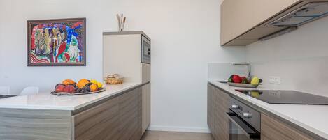 A modern kitchen with a wooden countertop, a built-in oven, and a wall-mounted painting.