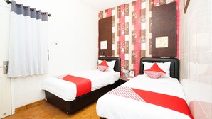 A hotel room with two beds, a wooden floor, a white door, and a patterned wall. - Hotel O Mojokerto Guesthouse (Mojokerto)