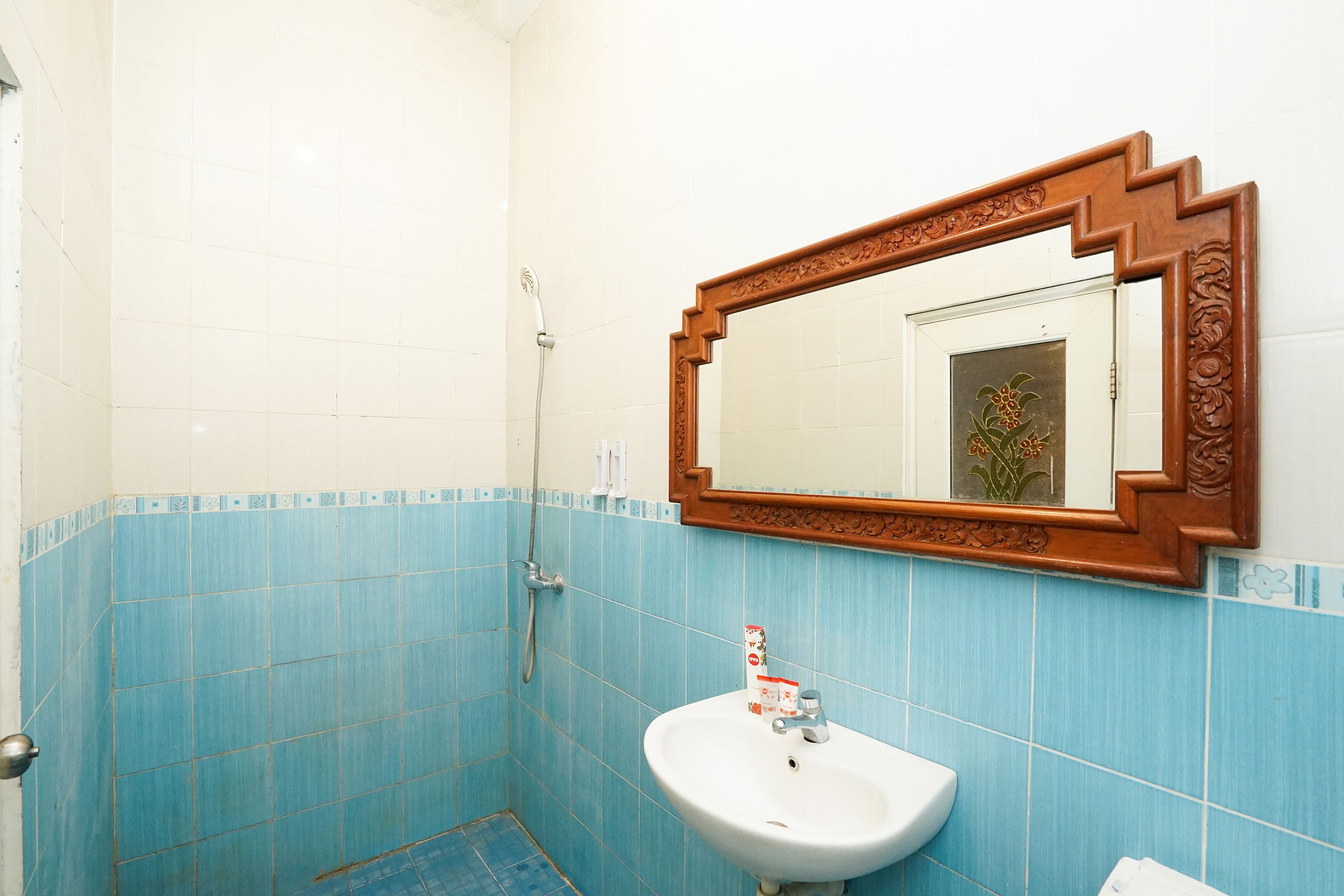 A bathroom with blue tiles, a white sink, and a wooden-framed mirror.