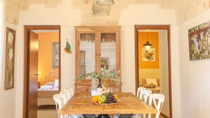 A dining area with a wooden table, white chairs, and a fruit basket. - TD Casale Del Vento in the Countryside with Pool (Monopoli)