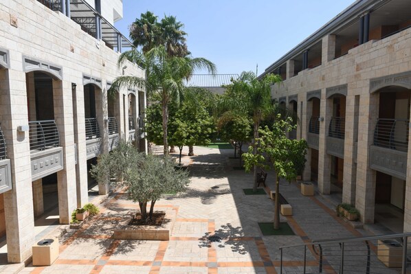 A courtyard with a central open space surrounded by buildings with arched doorways and balconies.