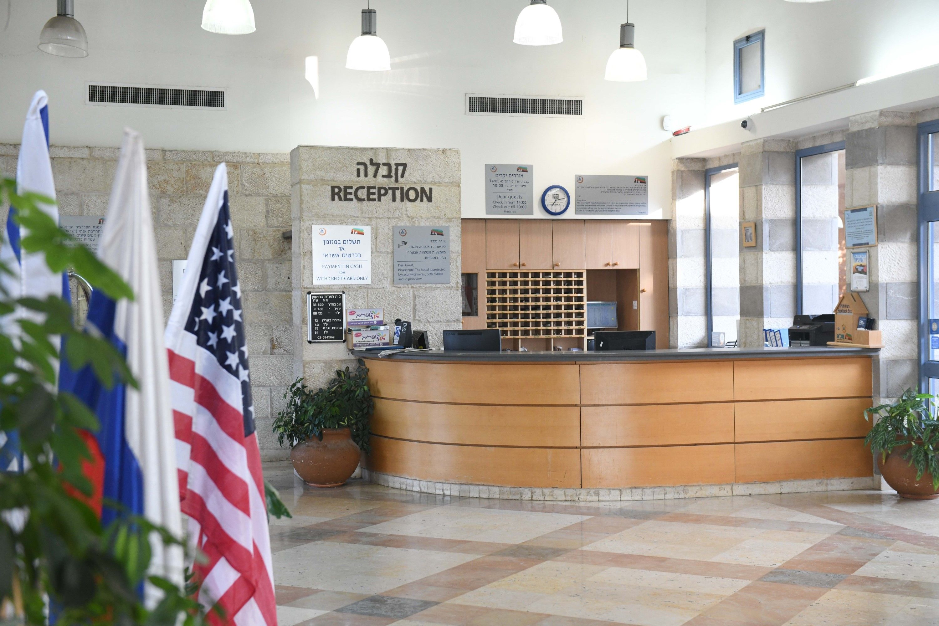 A reception area with a reception desk, American and Israeli flags, a clock, and informational signs.
