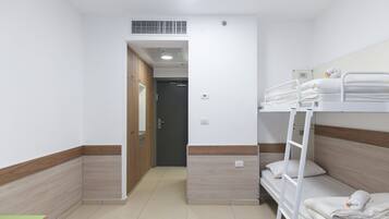 A hotel room with a bunk bed, a wooden wardrobe, and a small table.