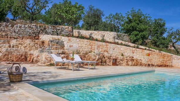 A swimming pool with lounge chairs and a stone wall. - TD Casale Terranova Stone Farmhouse with Pool (Monopoli)