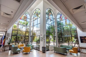 Un intérieur spacieux, doté de grandes fenêtres en arc de cercle, de plusieurs coins salon et d’une plante en pot.