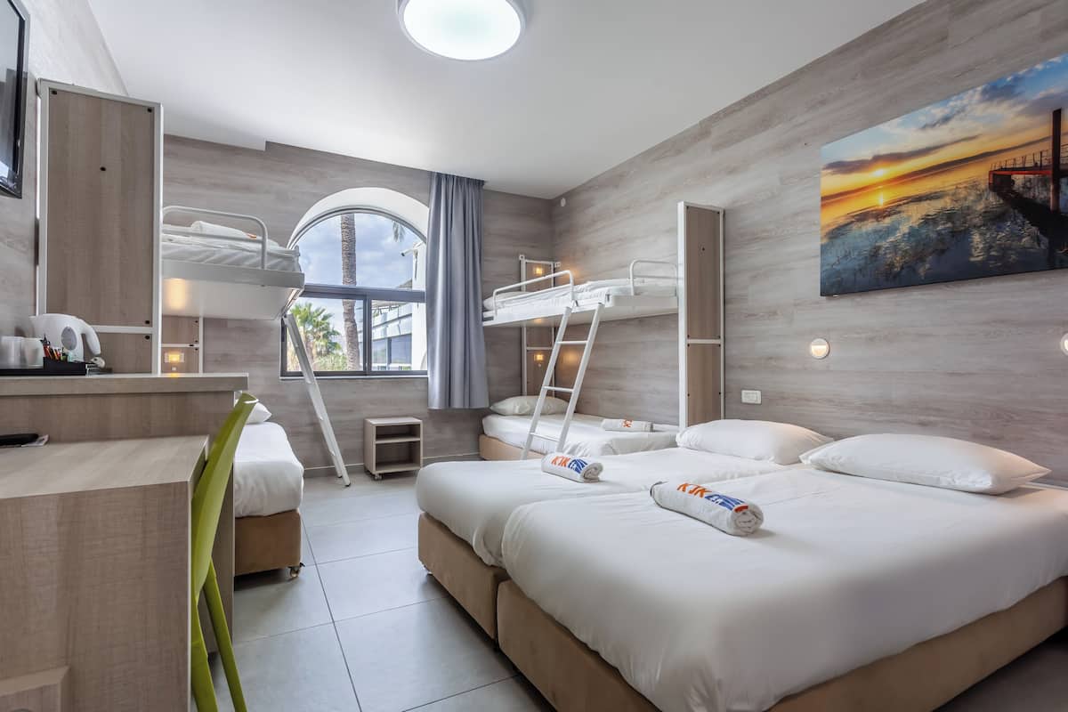 Een moderne hotelkamer met stapelbedden, een bureau, een stoel, een ladder en een schilderij van een zonsondergang.