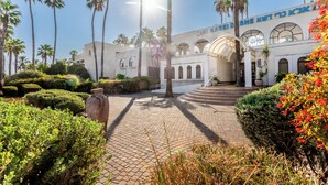 A building with arched windows and a central dome, surrounded by palm trees and well-maintained hedges. - HI Karei Deshe Hostel (Emek HaYarden)