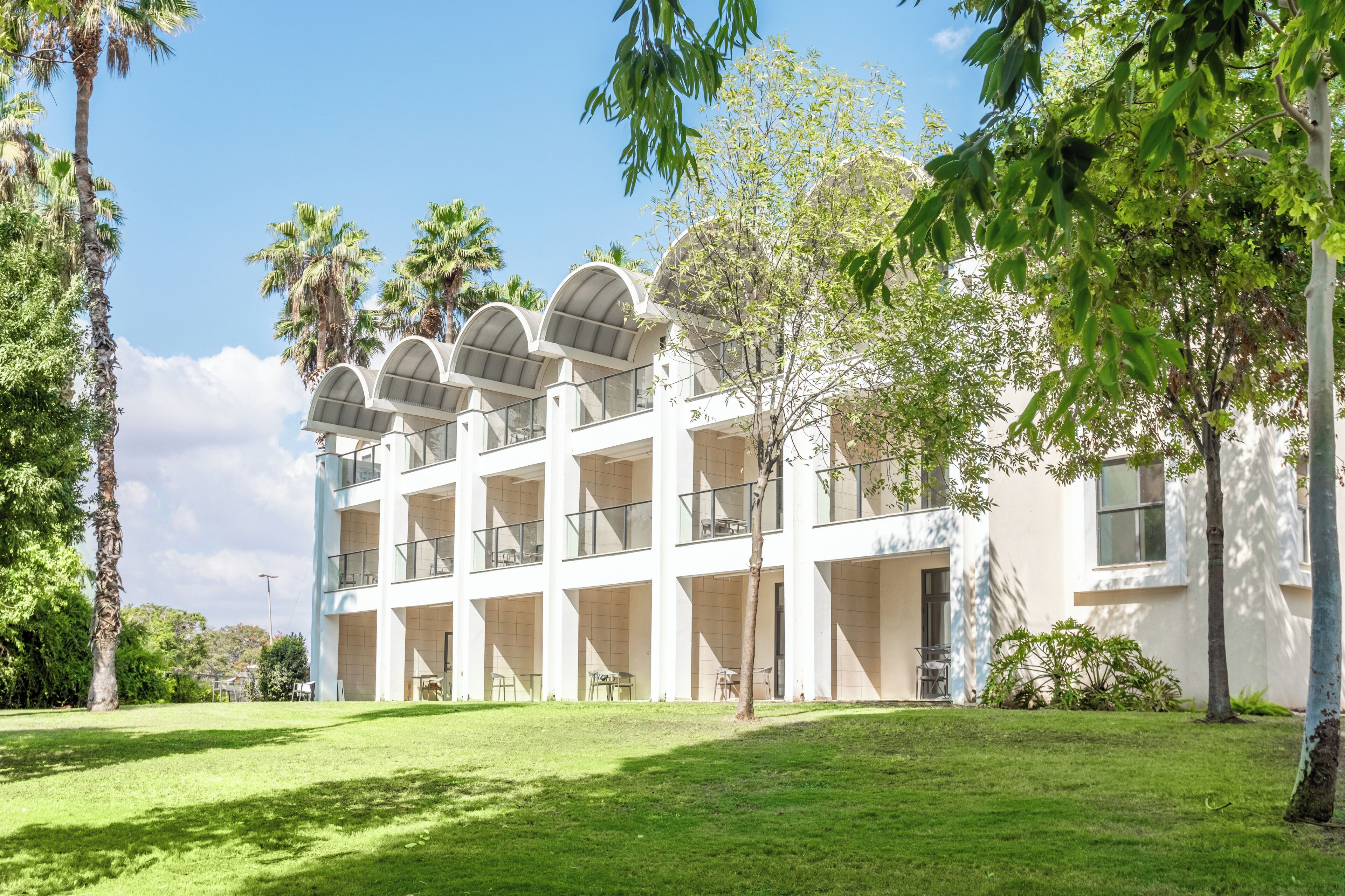 Ein mehrgeschossiges Gebäude im modernen Baustil, mit einem zentralen Atrium, Glasgeländern und mehreren Balkonen.