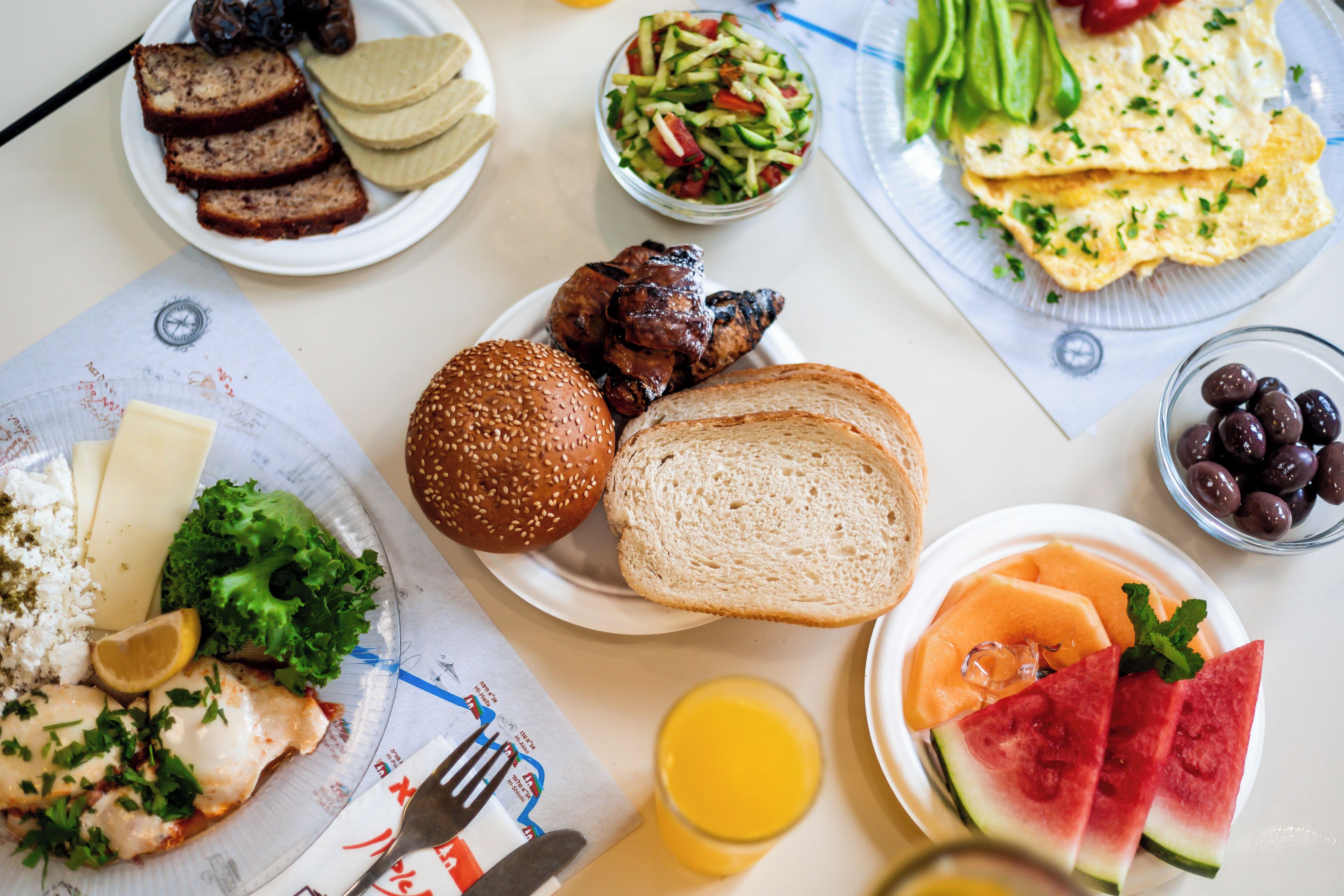 Una mesa con diferentes alimentos como pan, un sándwich y una ensalada.