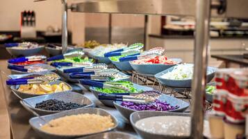 A buffet with various food items in bowls, arranged on a table.