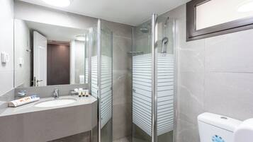 Une salle de bain moderne avec une douche à parois de verre, un lavabo avec un miroir et des toilettes ornées d’un autocollant bleu.