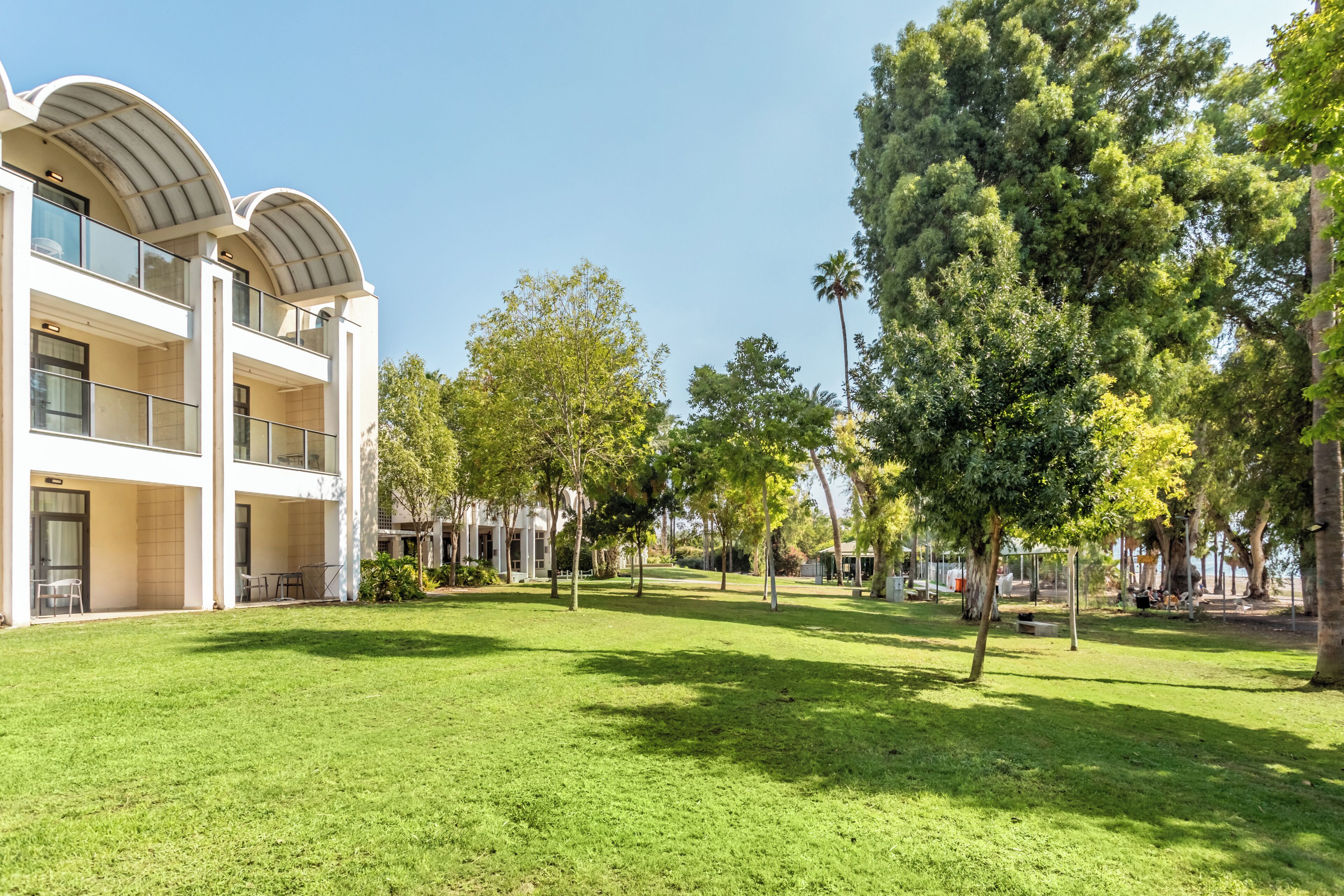 Un edificio moderno con techo plano y ventanas amplias, rodeado de un césped cuidado y árboles.