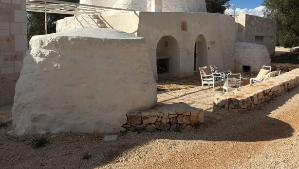 A traditional building with a dome structure, stone walls, and a seating area with chairs. - Dimora Casalino (Ostuni)