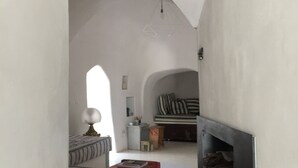 A narrow hallway with a fireplace, a bench, and a bed in the background. - Dimora Casalino (Ostuni)