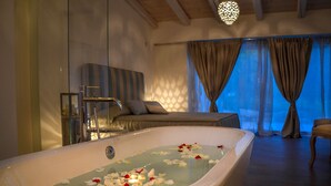 Ein modernes Badezimmer mit einer freistehenden Badewanne, einer Duschkabine aus Glas und einer Sitzecke mit Sofa und Sessel.