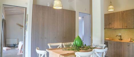 A dining area with a wooden table, white chairs, and hanging lights.