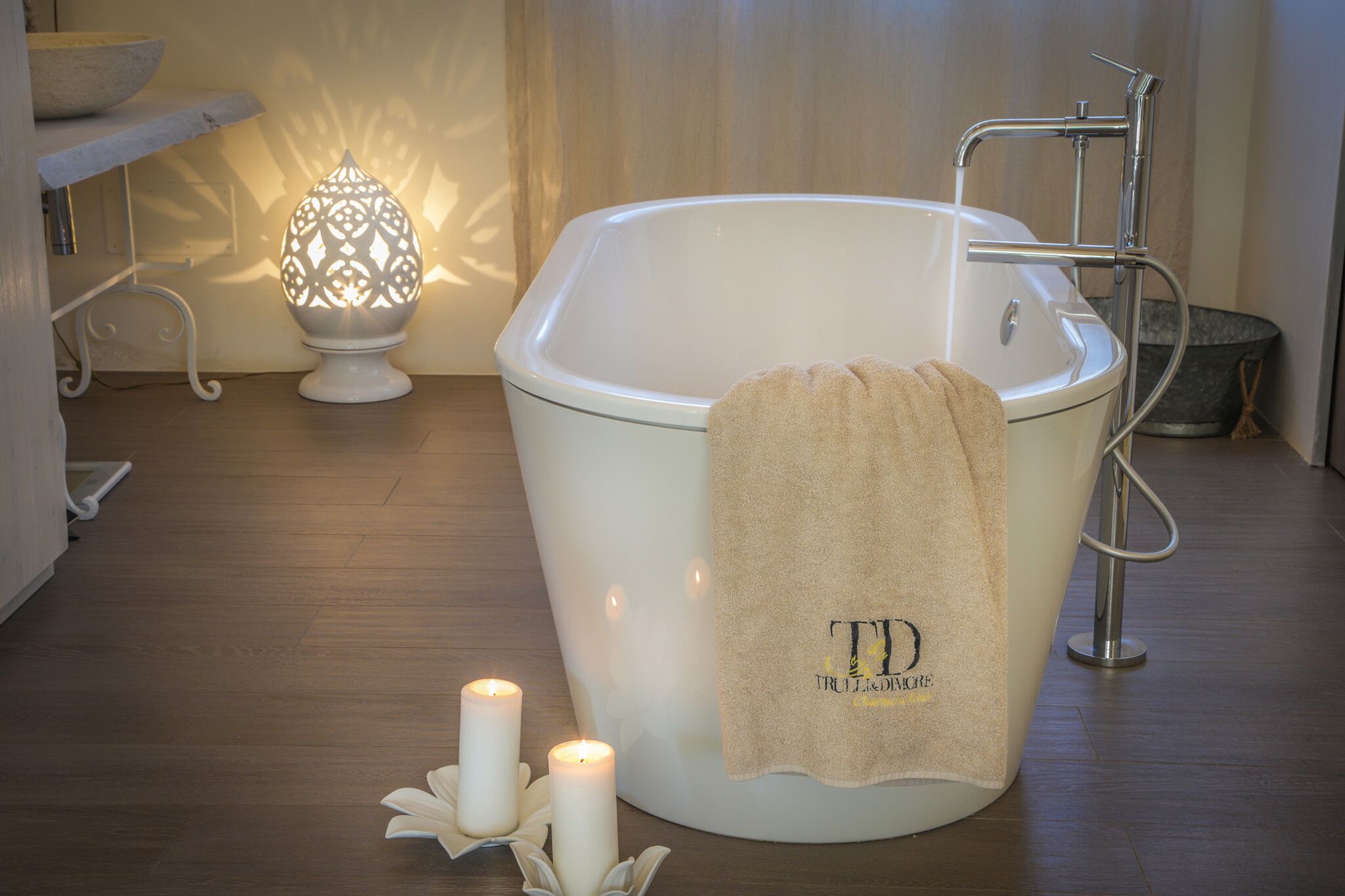 Un baño moderno con una bañera independiente, una toalla y velas.