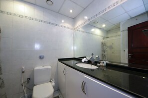 A bathroom with a white toilet, a sink with a black countertop, and a mirror above the sink.