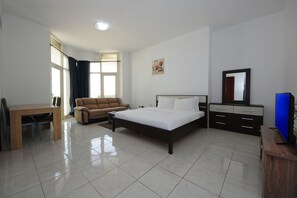 A bedroom with a bed, a sofa, a desk, and a dresser.