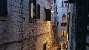 A narrow street with stone buildings, a bell tower, and a sign for the Muzej Grada Museum. - Palace Luxury Room (Split)