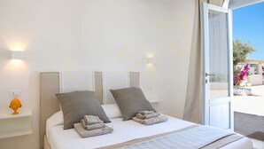 Un dormitorio con cama, almohadas y mesita de noche.