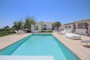 Una piscina al aire libre, sillones reclinables de piscina